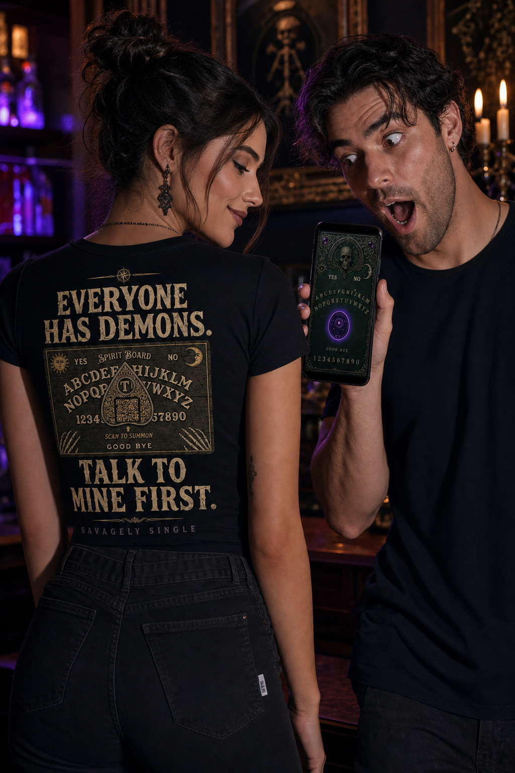 Spirit Board shirt - woman showing back design, man shocked reading gothic board game on phone